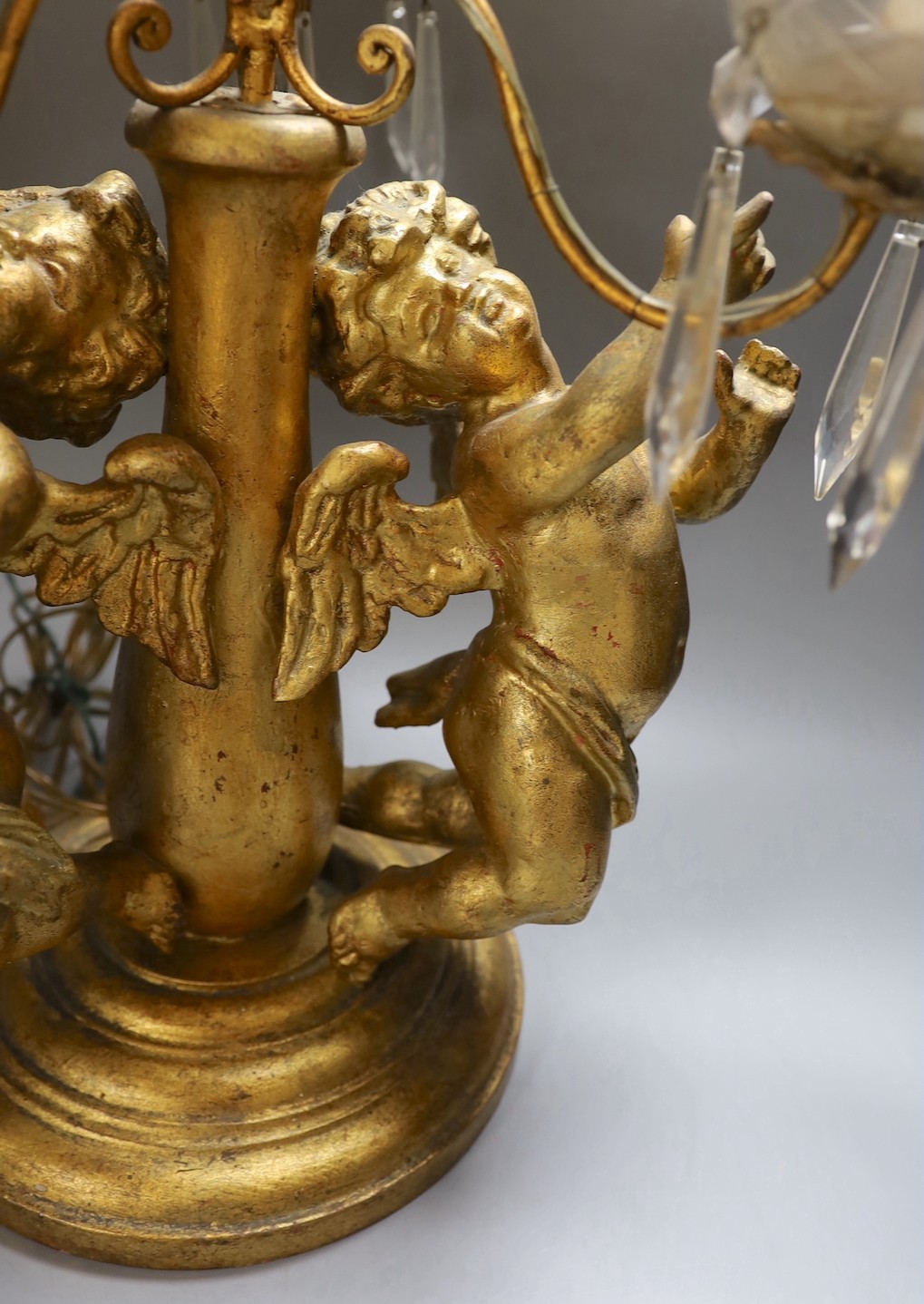 An Italian three branch gilt composition cherubic lamp with cut glass lustre drops - 64cm high